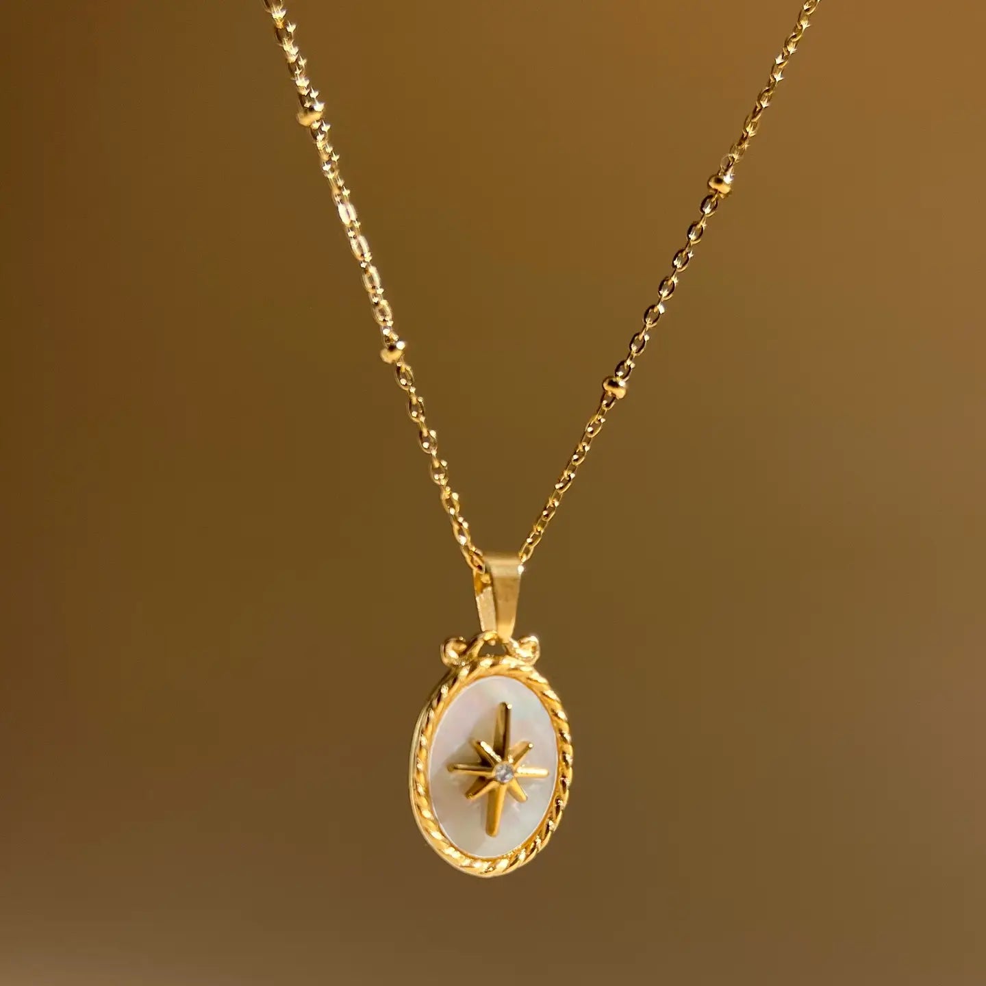 Collana in acciaio con pendente ovale in madreperla con stella e strass.